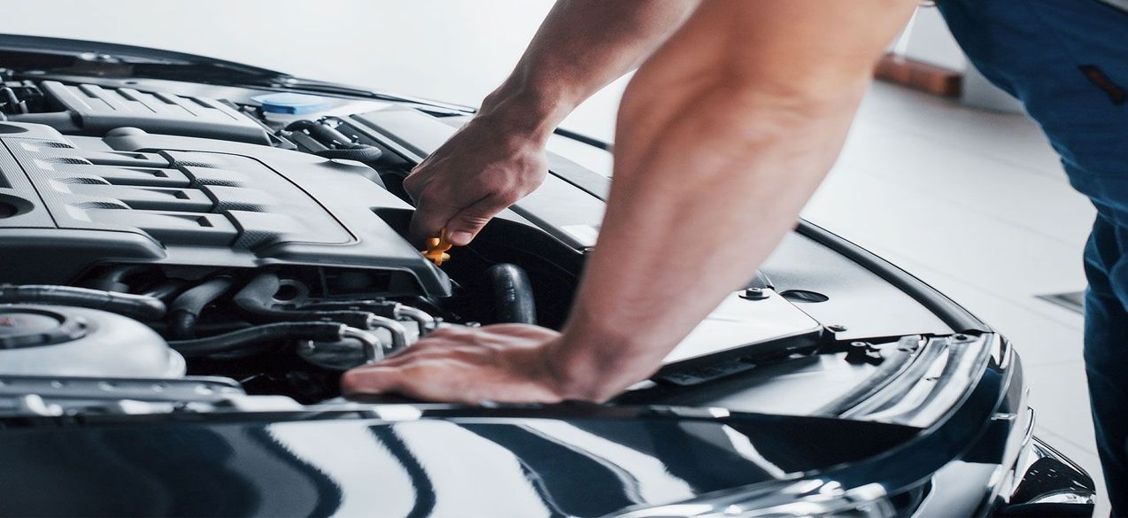 Eine Hand schraubt in einem Motorraum eines Autos rum